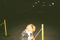a person standing in a parking lot holding a cell phone