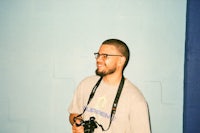 a man holding a camera in front of a blue wall