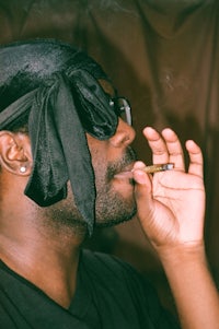 a man wearing a black bandana smoking a cigarette