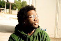 a man wearing glasses and a green hoodie
