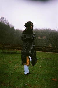 a person in a black coat standing in a field
