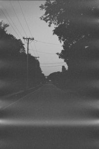 a black and white photo of a street with power lines